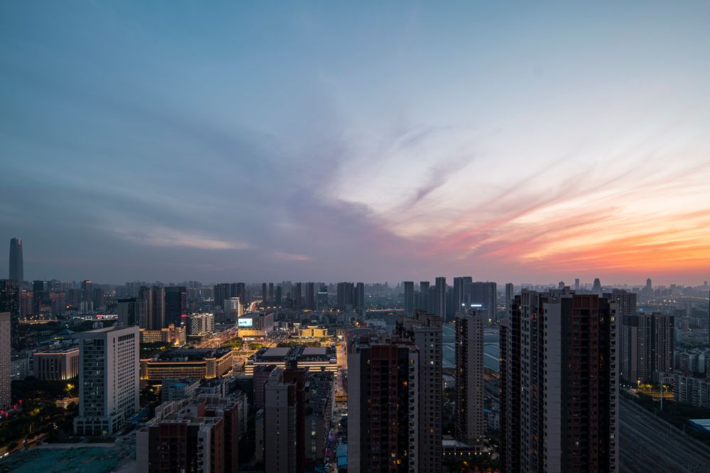 Aerial view of a city skyline at sunset with warm light over the high-rise towers.