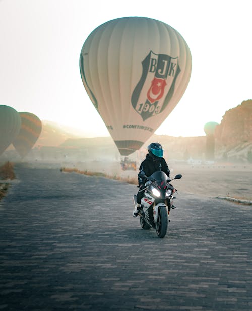 Motorcyclist Riding on the Road Through the Hot Air Balloon Landing Site
