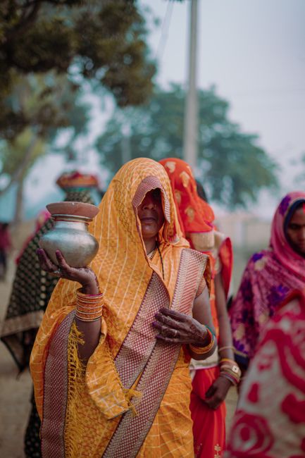 A South Asian woman in traditional clothing holding a pot outdoors in Ghazipur, India.