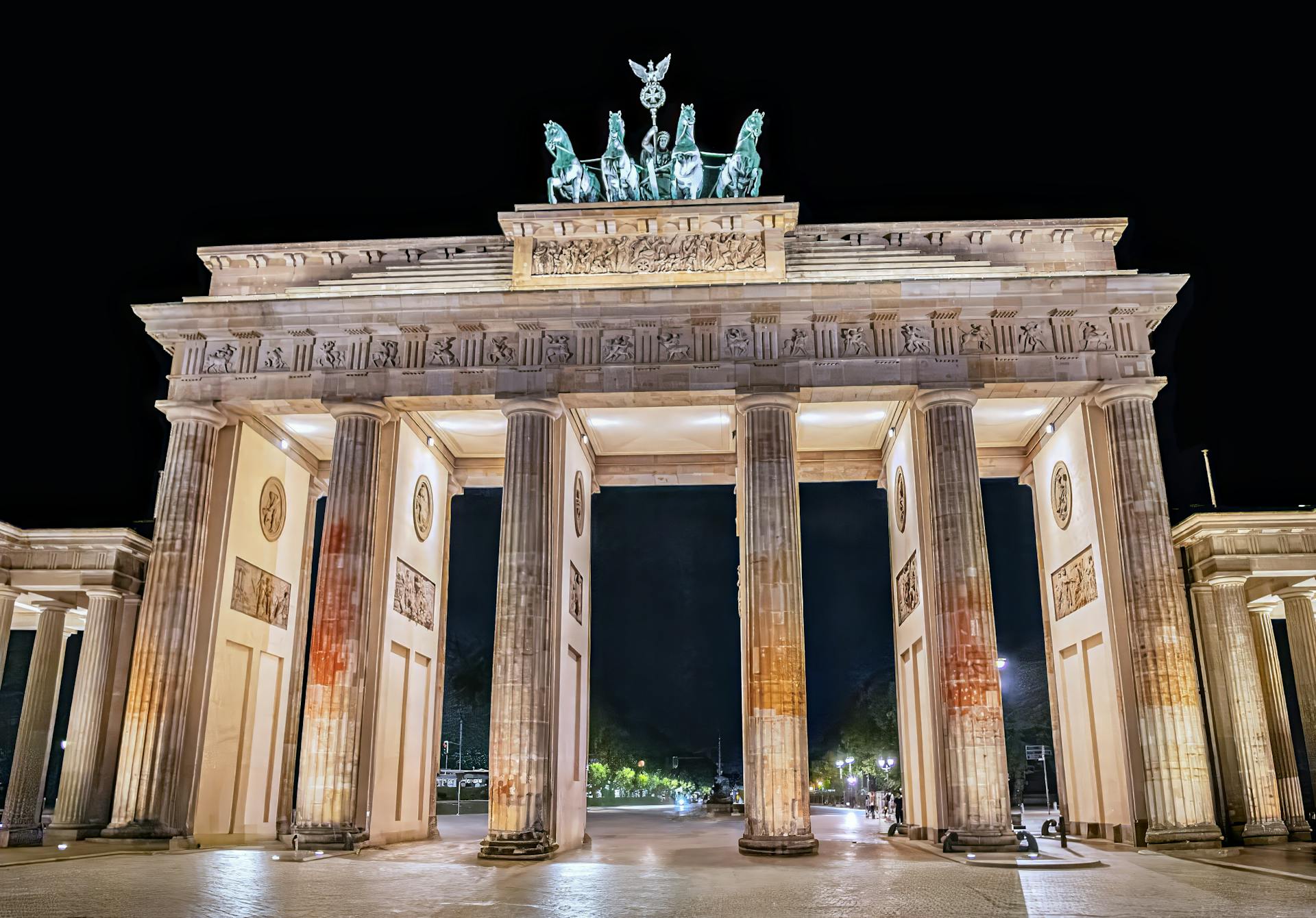 Night view of the illuminated Brandenburg Gate in Berlin, showcasing its neoclassical architecture.