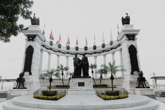 A historic monument featuring statues and flags in Guayaquil, Ecuador symbolizing independence and unity.