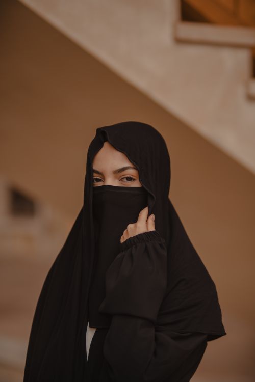 Free Elegant portrait of a woman wearing a black niqab, showcasing cultural attire indoors. Stock Photo