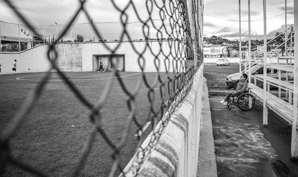 Black and white photo of a soccer field in Atlacomulco, Mexico with a wheelchair spectator.