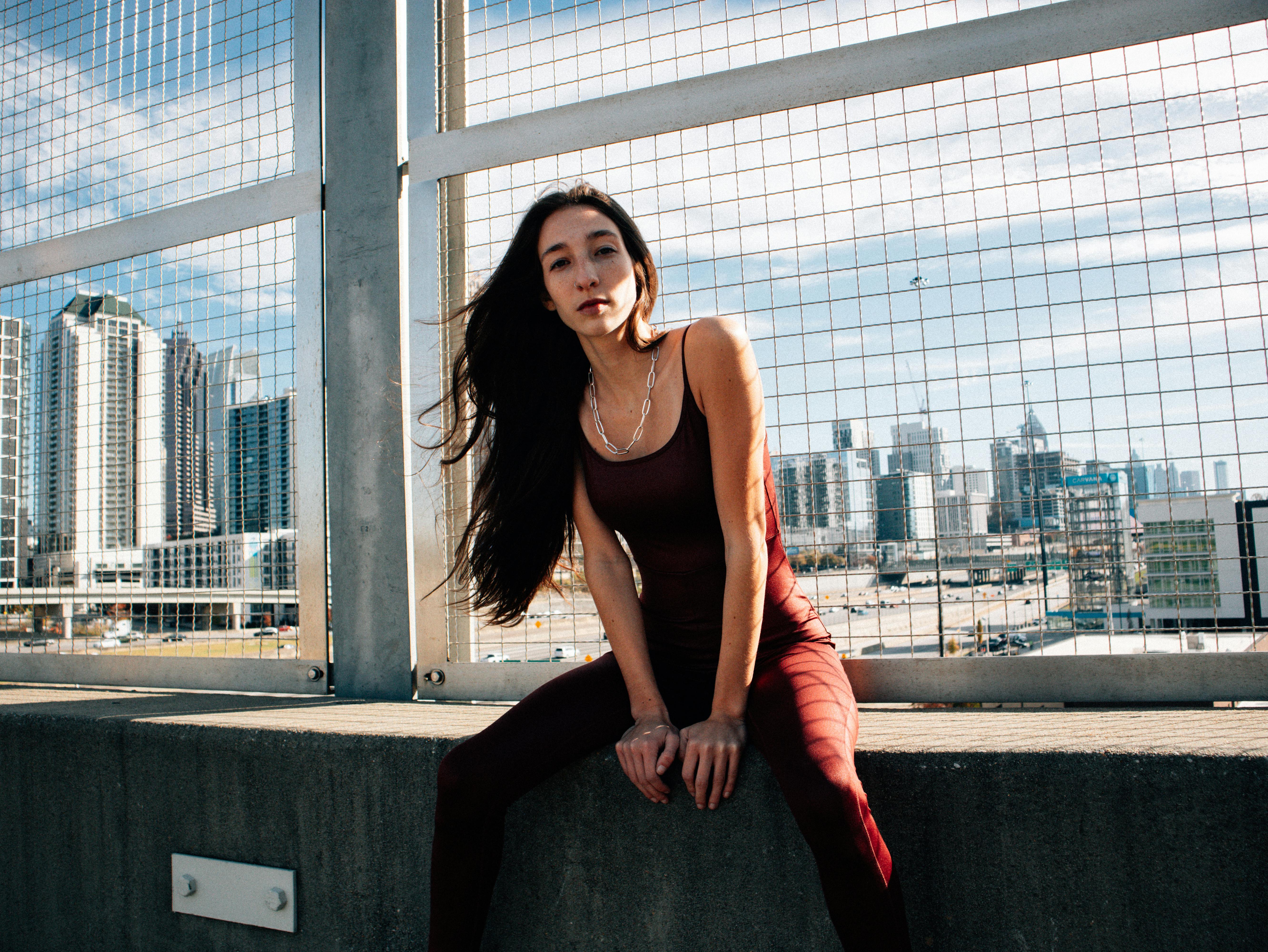 beautiful fashion model sitting on concrete ledge with city view