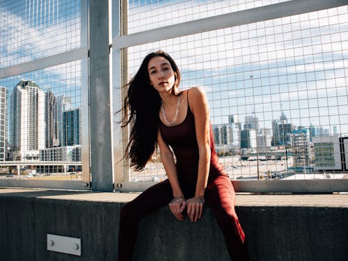 Beautiful fashion model sitting on concrete ledge  with city view 