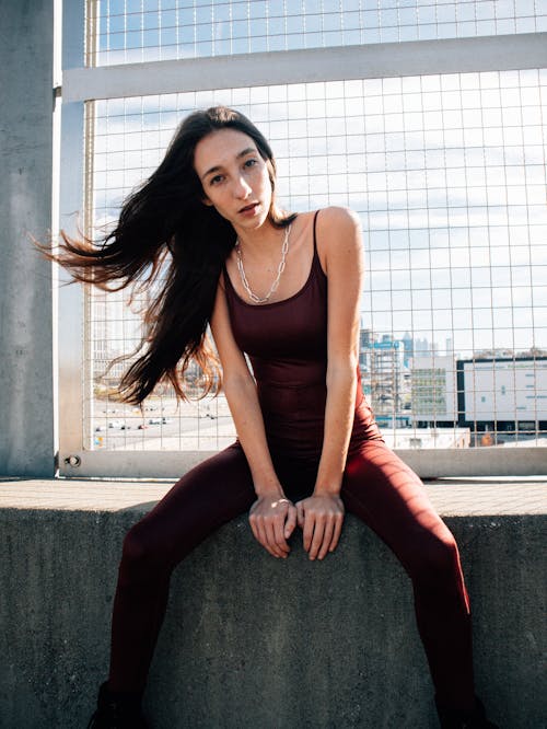 Beautiful fashion model sitting on concrete ledge  with city view