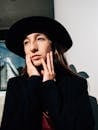 一位戴着黑色帽子、带着电影般的灯光和深思熟虑的表情在户外摆姿势的女人