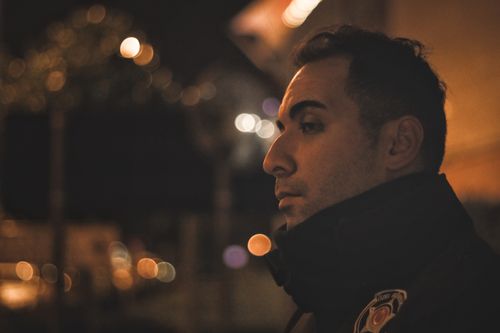 Free Dramatic side profile portrait of a man in an urban night setting. Stock Photo