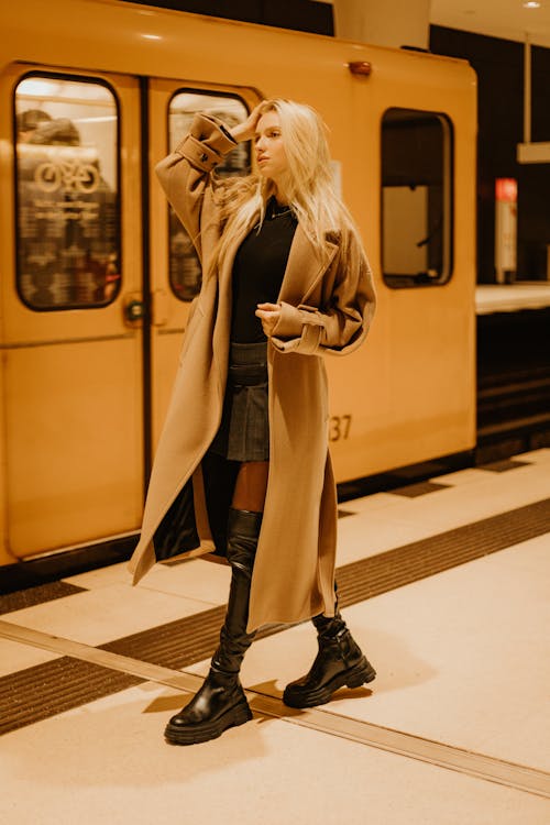 Young Woman in a Coat and Boots Walking on a Subway Platform 