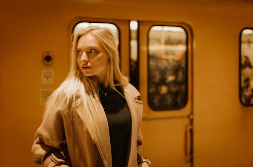 Young Woman in a Coat Standing on a Subway Platform 