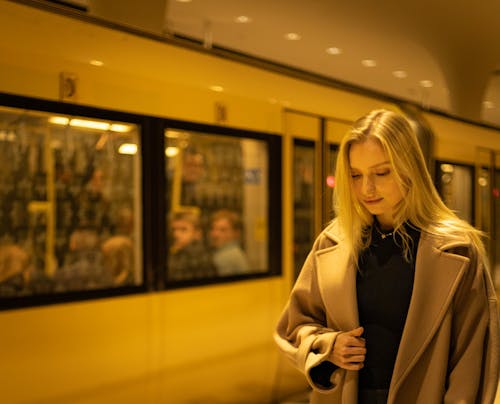 Blonde Woman in Beige Coat Standing at a Train Station