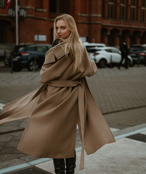 Free Stylish blonde woman in a coat confidently posing on a city street. Stock Photo