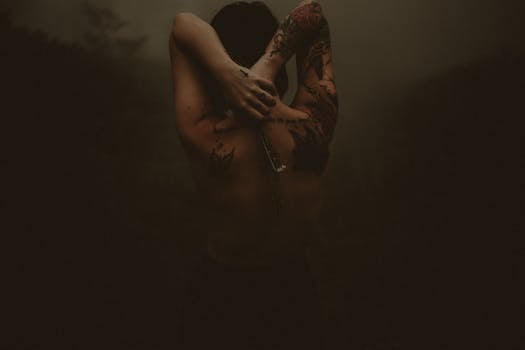 Moody artistic portrait showcasing a tattooed person from behind in dark ambiance.