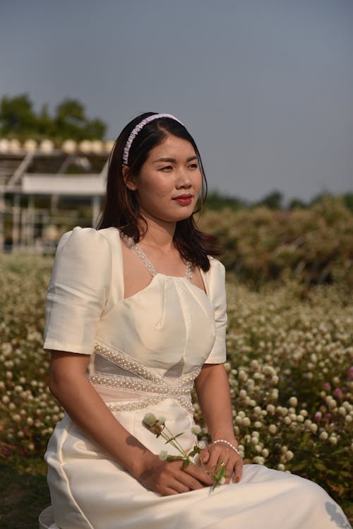 Bride in Wedding Dress Sitting on Meadow