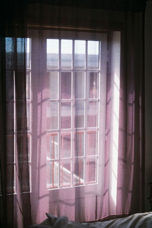 Free A serene view of sunlight streaming through sheer curtains in a cozy room in Nazaré, Portugal. Stock Photo