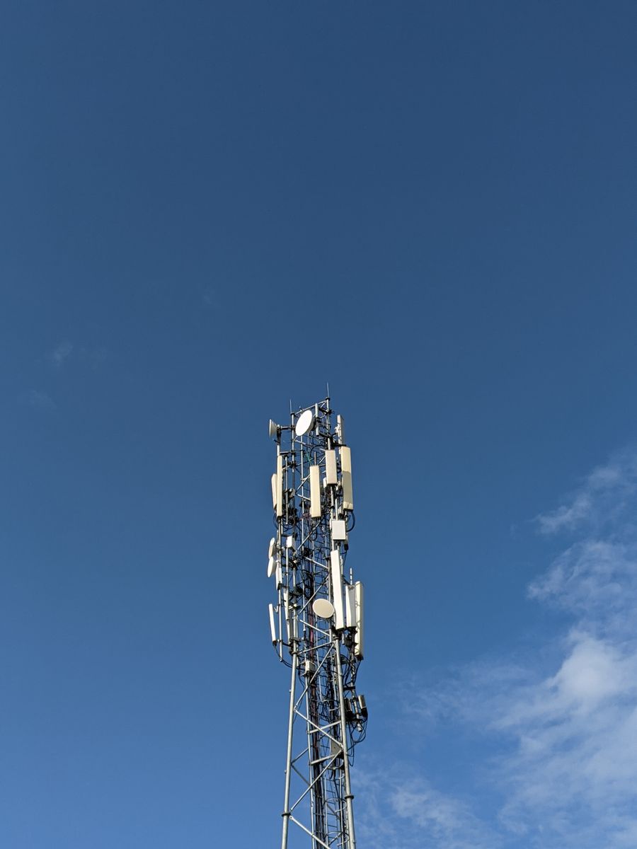 Mobile telecom tower with antennas against a clear blue sky in Uttar Pradesh, India