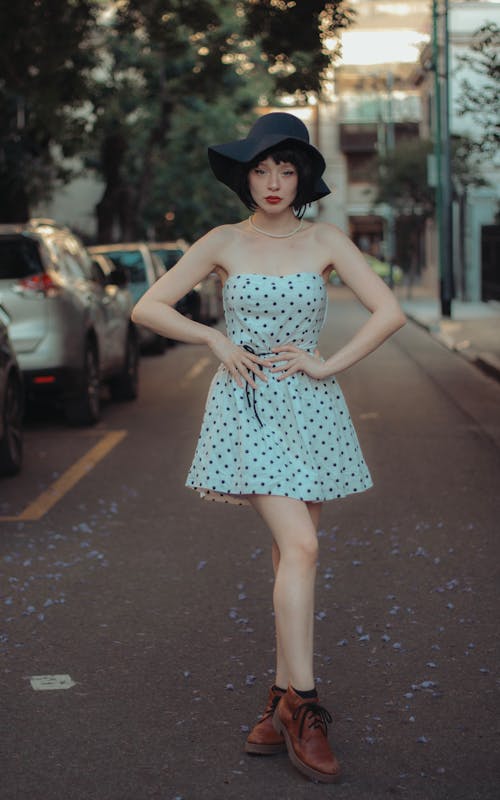 Young Woman in a Polka Dot Dress and Hat Standing on the Street 