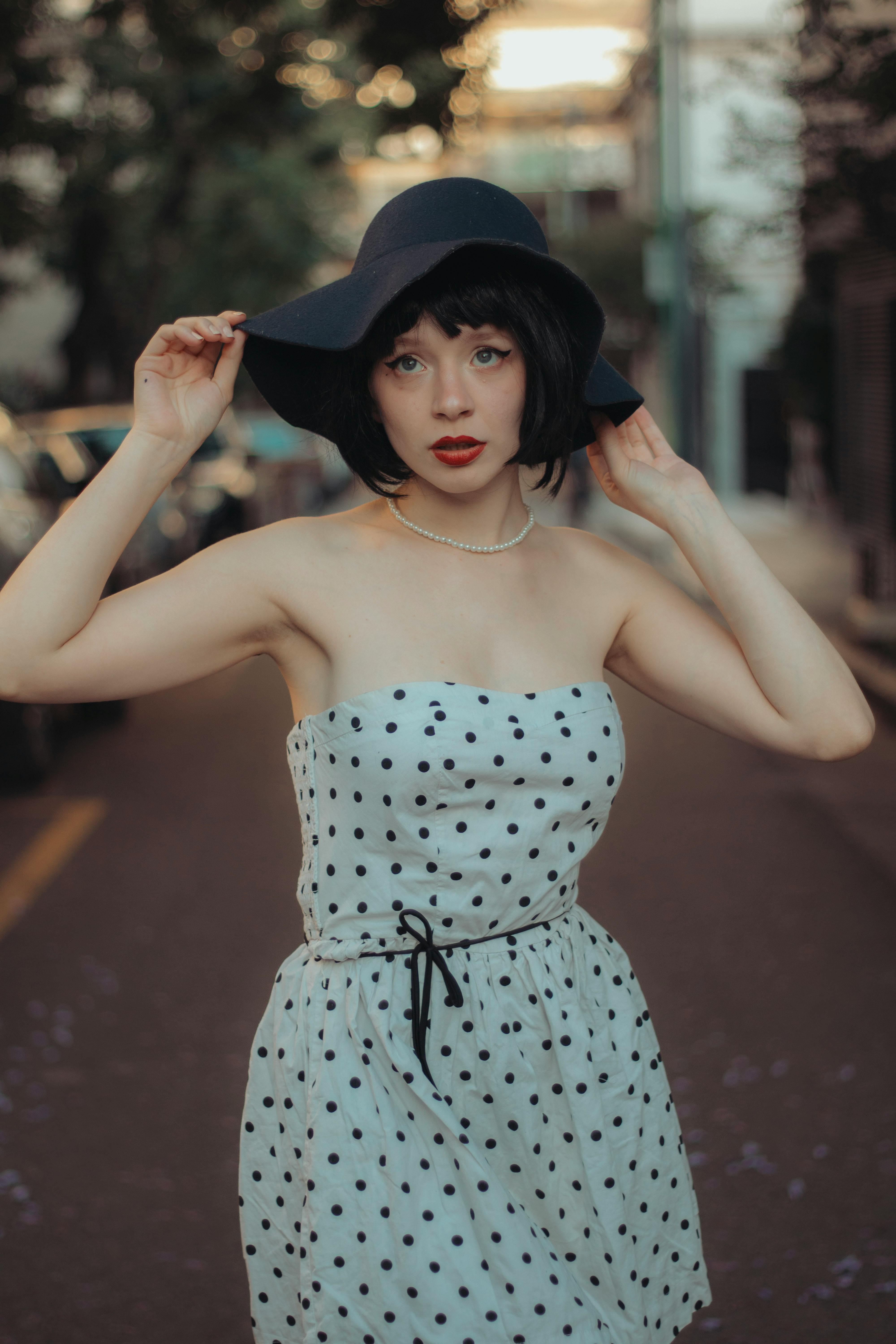 Model in a White Off-the-Shoulder Dress with Polka Dots Holding Her Soft  Brim Hat · Free Stock Photo