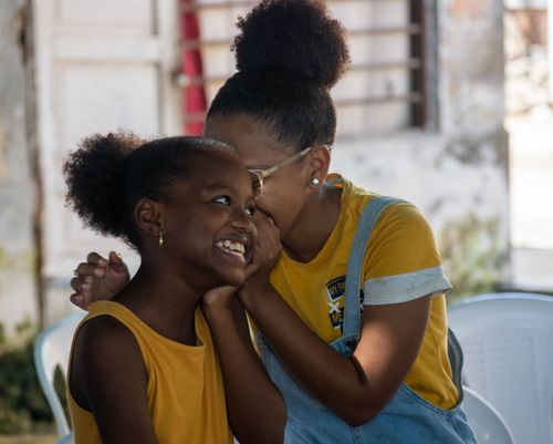 Free Two girls happily whisper and laugh, capturing a moment of friendship and joy. Stock Photo