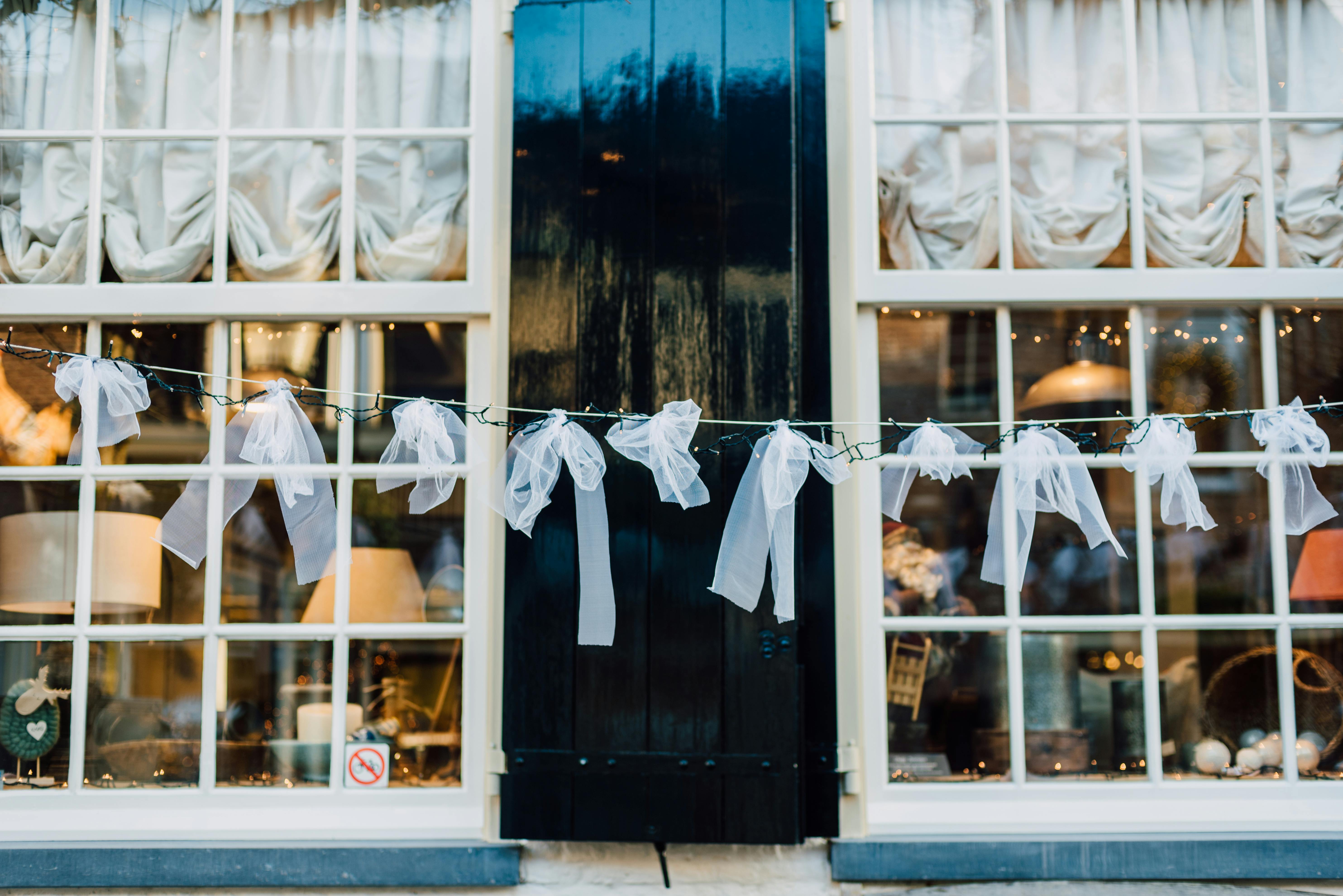 Elegant window display of a boutique with tulle and lights, creating a cozy and inviting atmosphere.