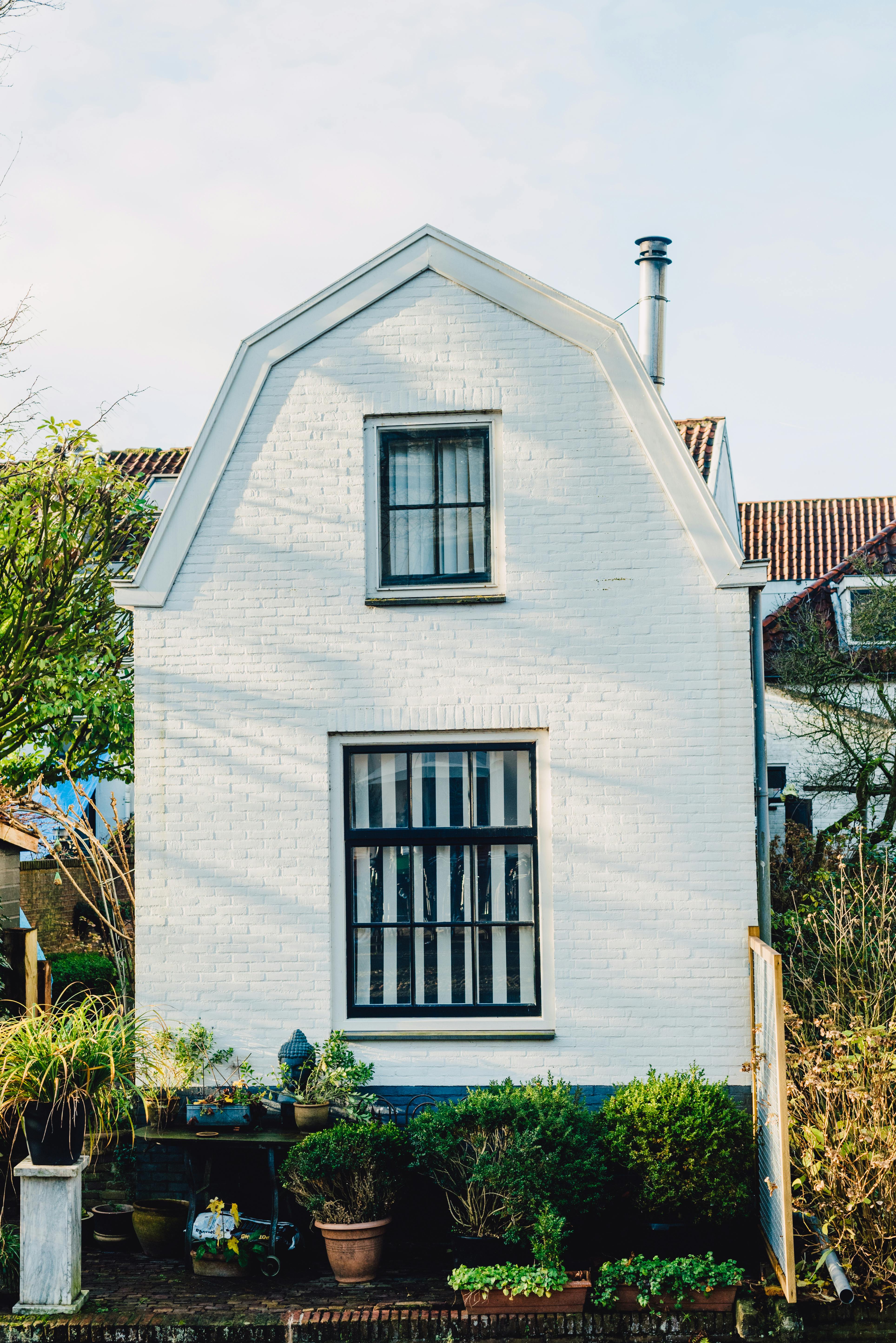 A cozy white house with potted plants and a garden, ideal for urban living.