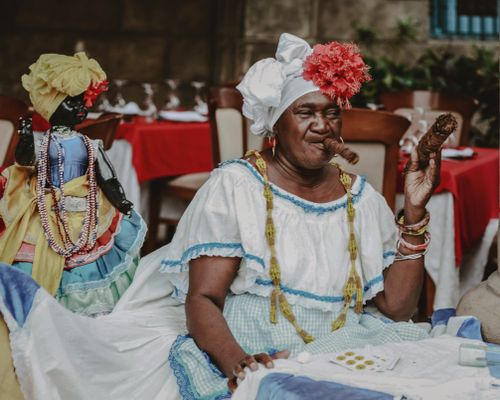 Free Elderly woman in traditional attire enjoying a cigar at a Cuban restaurant. Stock Photo