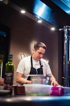 Chef in a modern restaurant kitchen focused on preparing a gourmet dish.