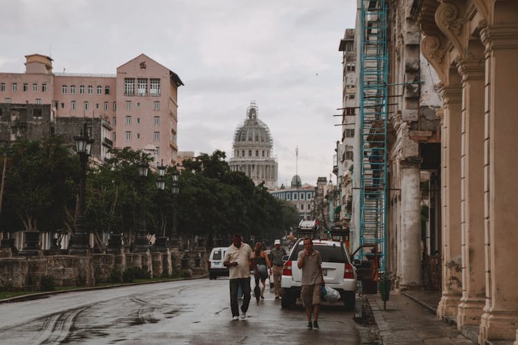 Men Walking On Street With Buildings And Dome Behind