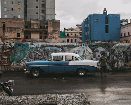 Classic blue vintage car parked on a graffiti-adorned urban street, capturing city life.