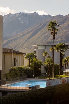 A picturesque view of Locarno, Switzerland featuring a luxurious pool and stunning mountain backdrop.