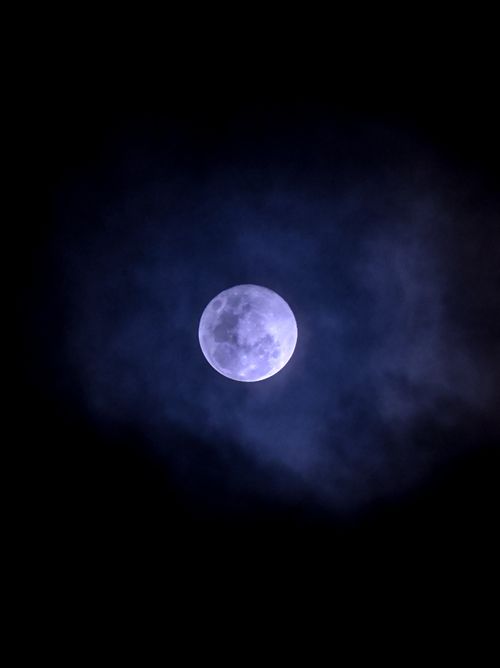 Free A serene view of the full moon illuminating the cloudy night sky in Cuenca, Ecuador. Stock Photo