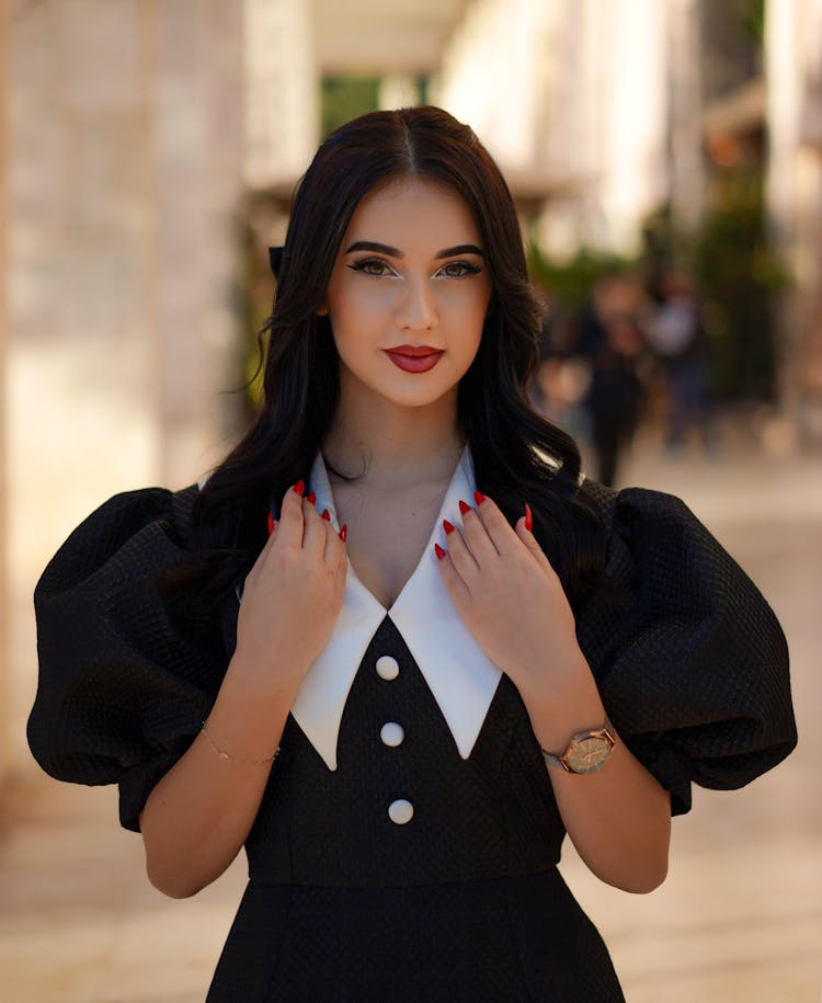 Beautiful Model In A Retro Black Dress With Puffy Sleeves And A Wide White Collar In The Hall Of A Shopping Mall