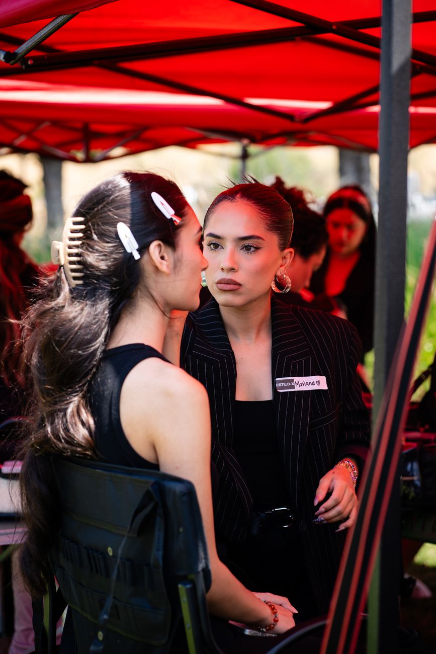Models gathered backstage in dark tailoring before a runway call