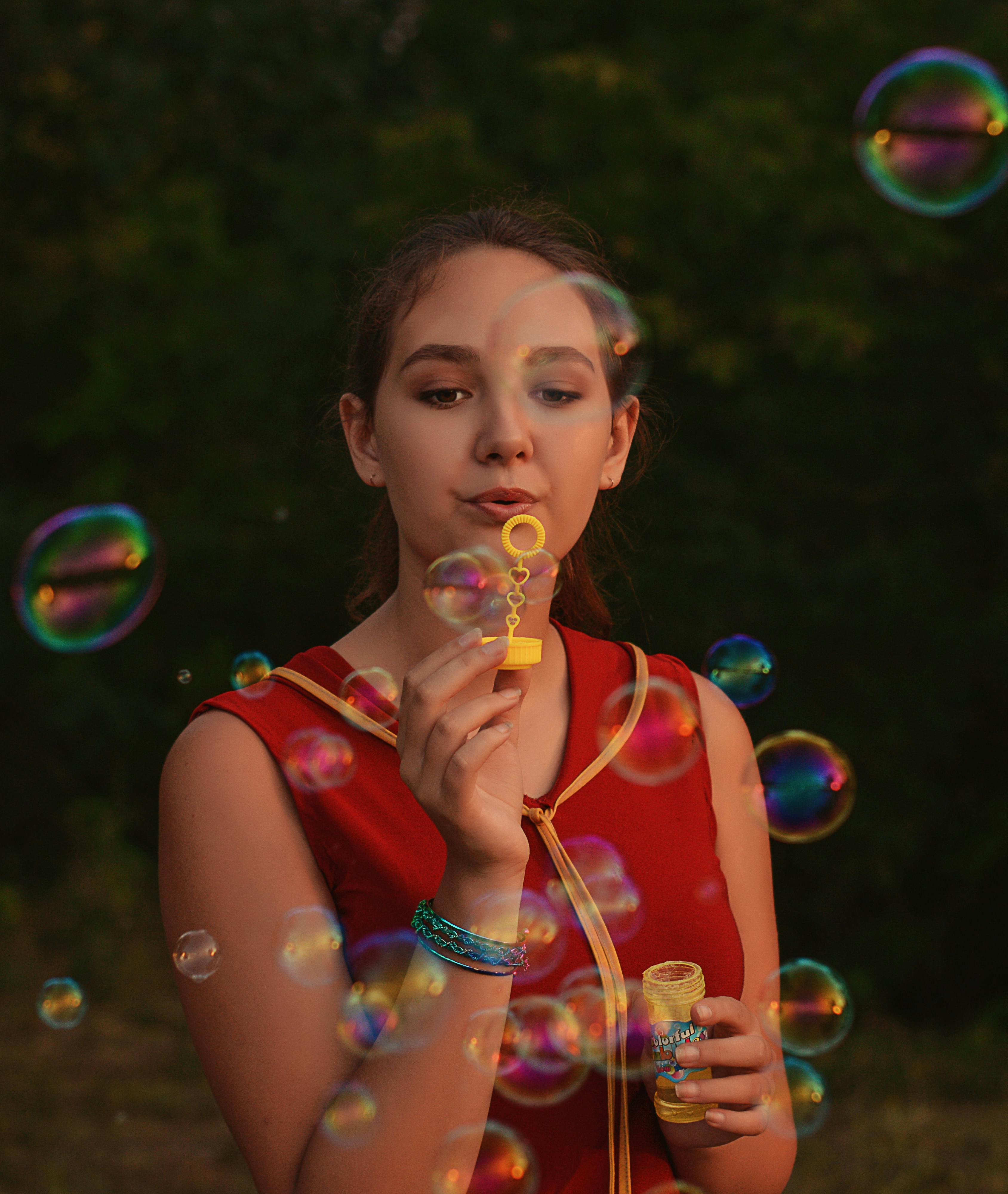 A young woman enjoys blowing bubbles in a sunny park, capturing the essence of summer fun.