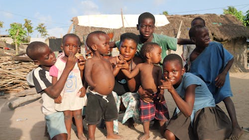 Photo of a Woman with Group of Boys Posing in a Village