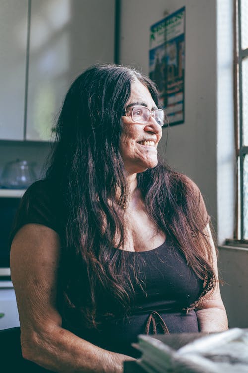 Elderly Woman Sitting by the Window and Smiling 