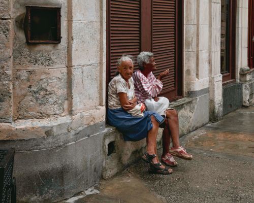 Free Two senior women sitting outside a traditional townhouse, capturing urban tranquility. Stock Photo