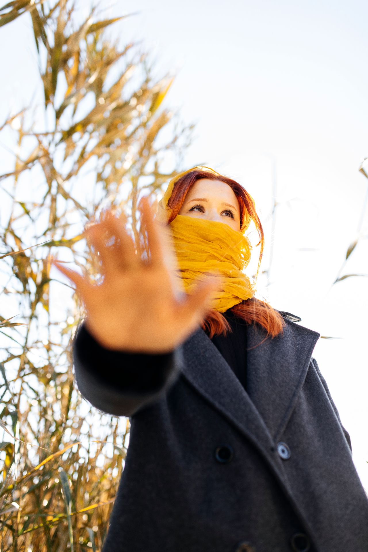 Woman with a yellow scarf wrapped high over her nose and a gray coat