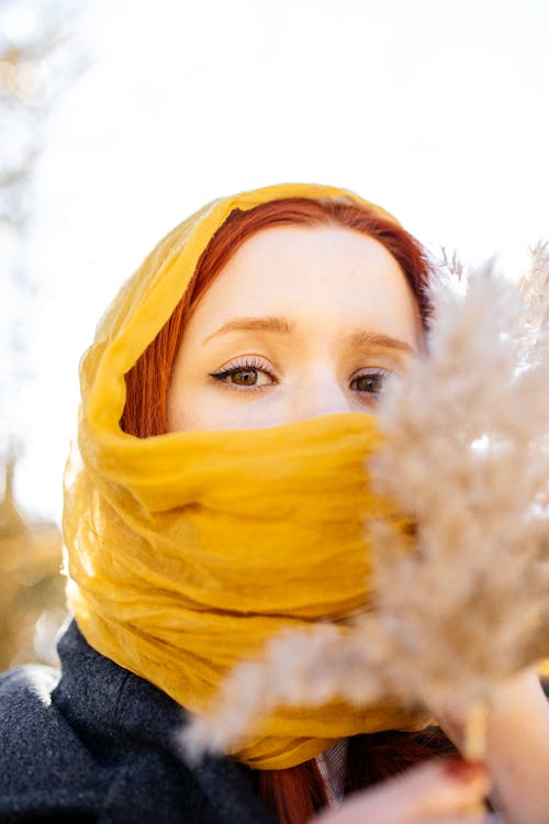 Young Woman Wearing a Yellow Scarf Holding a Piece of Ornamental Dry Grass