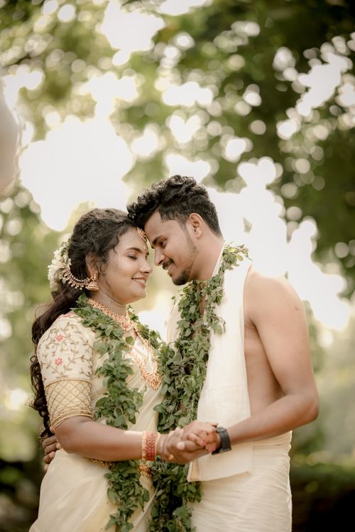 Free A romantic couple embracing outdoors in traditional wedding attire with natural greenery. Stock Photo