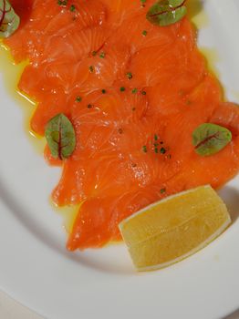 Delicious salmon carpaccio garnished with lemon and greens, perfect for food photography.
