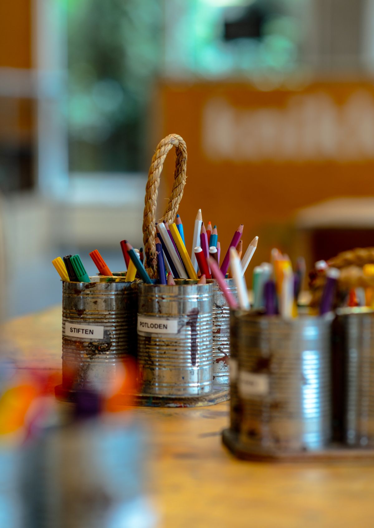 Colored pencils organized by color in recycled tin cans