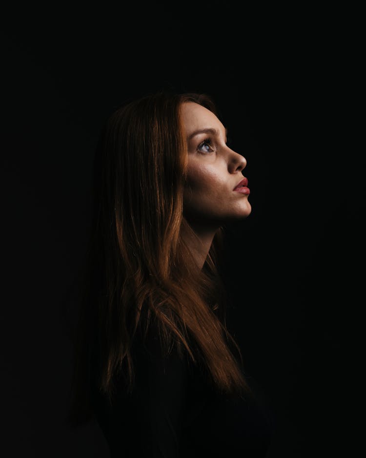 Woman In A Dark Room Looking Up In Profile