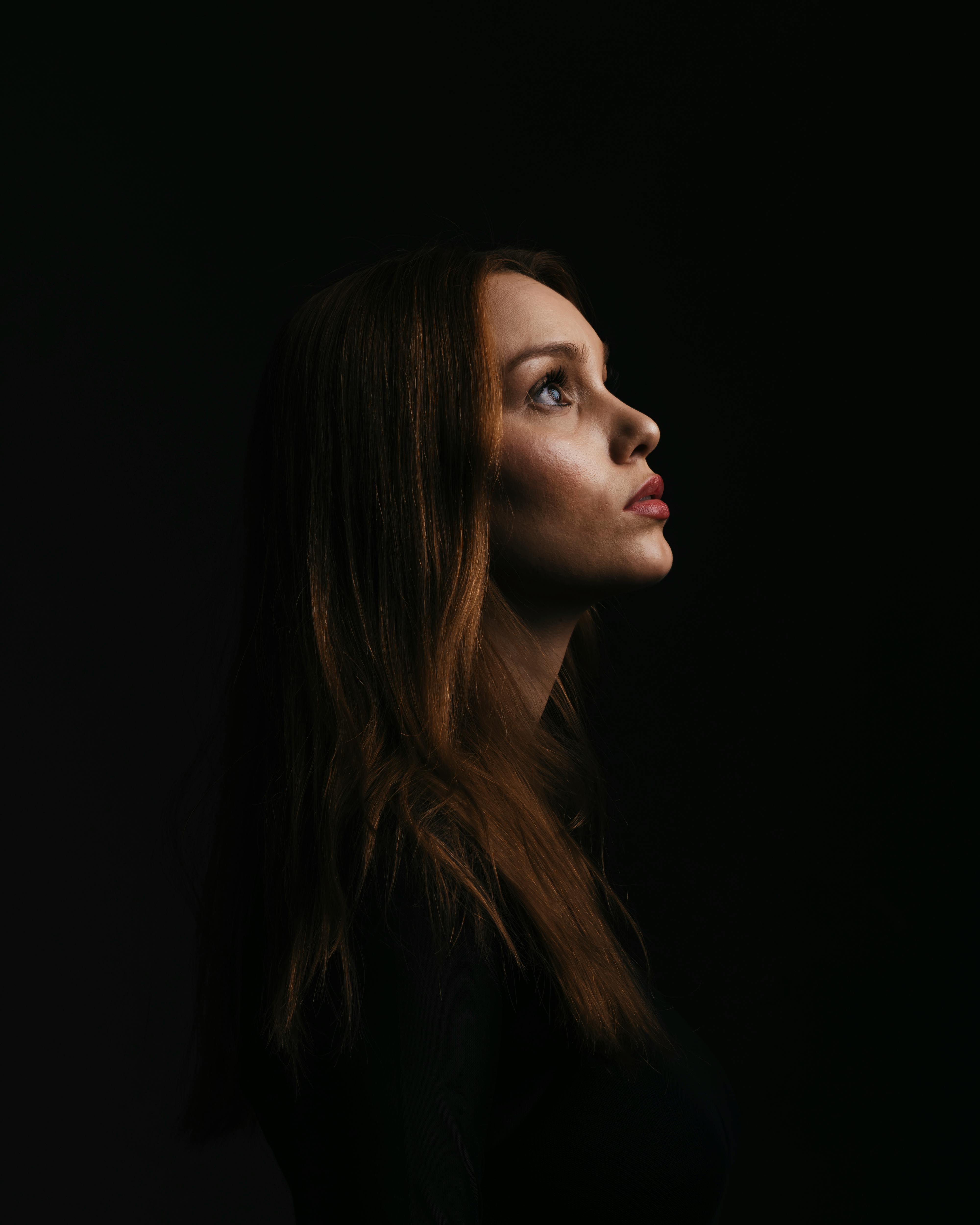 Woman in a Dark Room Looking Up in Profile · Free Stock Photo