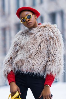 Stylish woman wearing fur coat and red beret posing outdoors.
