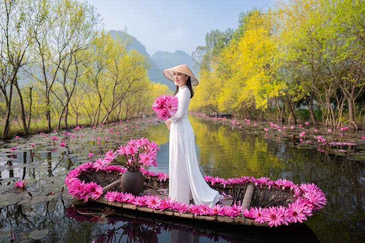 Woman In White Dress And With Flowers Standing On Boat On River