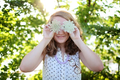 Free Woman Wearing White and Black Dotted Sleeveless Top Holding White Flower Stock Photo