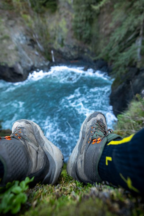 Free Hiker's perspective from the edge of a rugged cliff over a turbulent blue ocean. Stock Photo