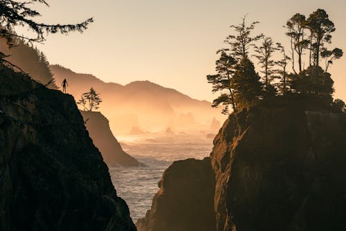 Person Standing on Rocks on Sea Coast