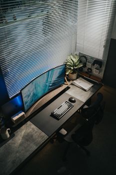 Stylish home office desk with a curved monitor, keyboard, and decorative elements.